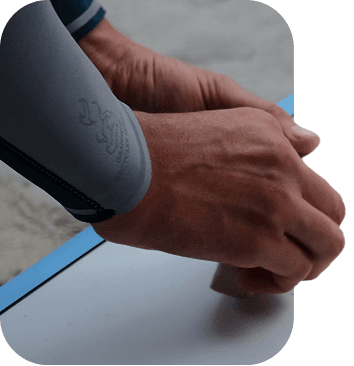 Hands waxing a surfboard